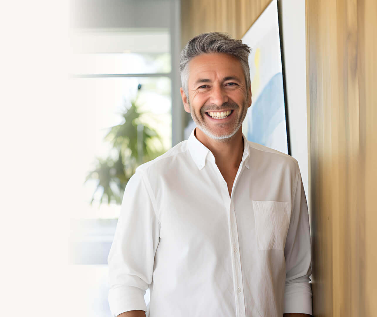 A group of students in caps and gowns stand on stage at a graduation ceremony, holding diplomas and smiling for a photo. A red curtain and a banner are in the background.